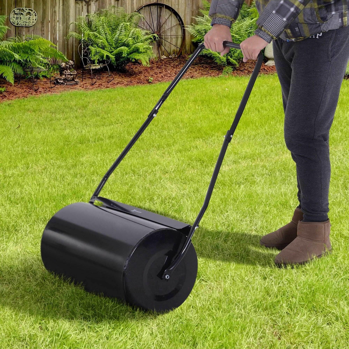 Black lawn roller on grass with long U-handle for push-and-pull