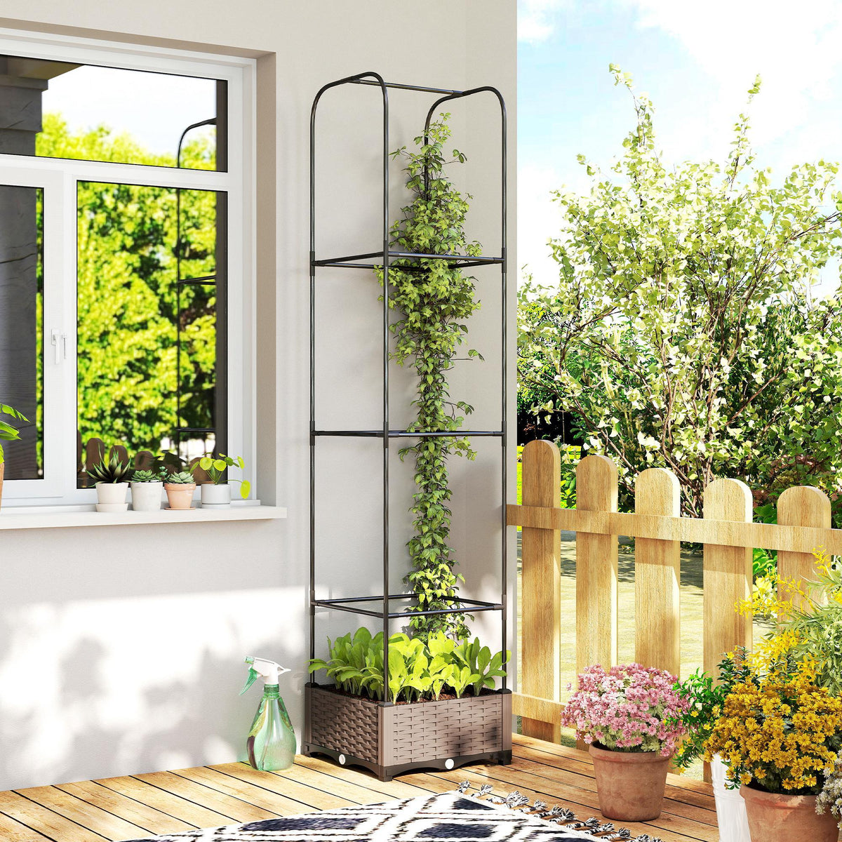 Gray plastic raised garden bed with trellis, dense plants and blooming flowers on deck