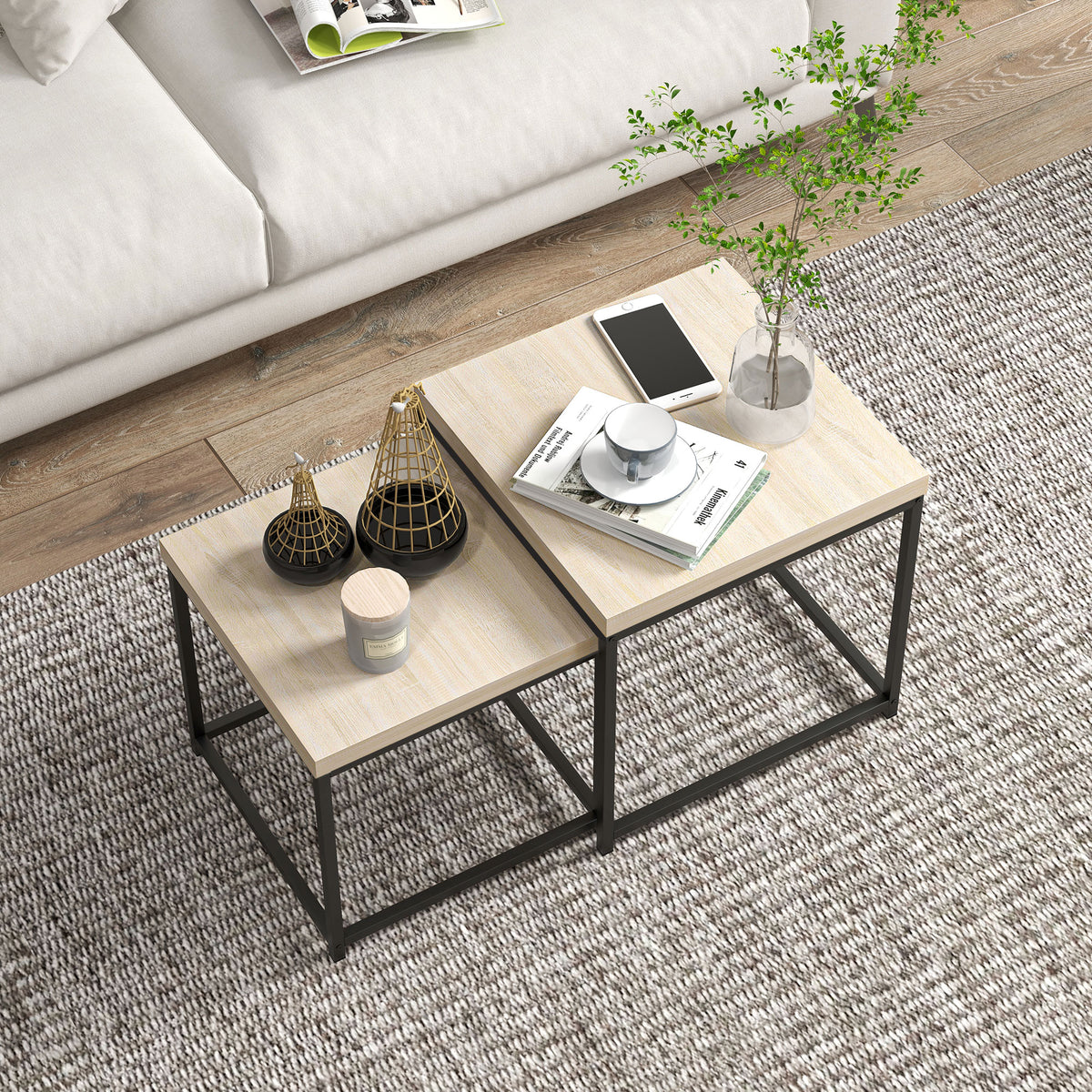 Nesting coffee table set of 2 with light oak tops and black frames on a rug