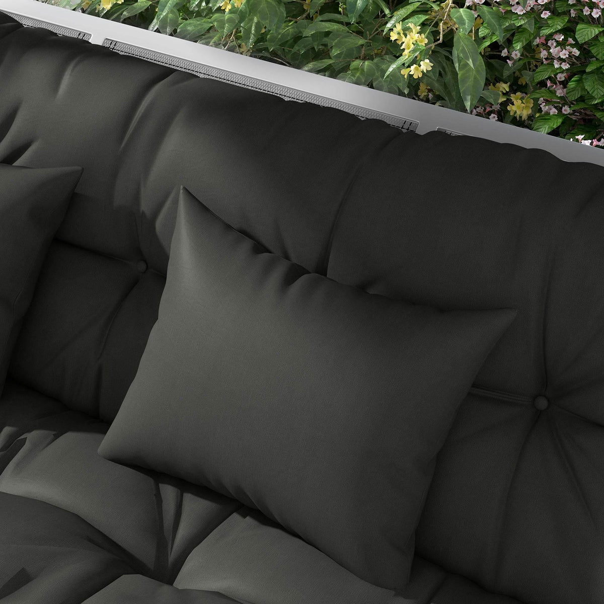 Dark grey patio cushion and square pillow close-up with tufted seams