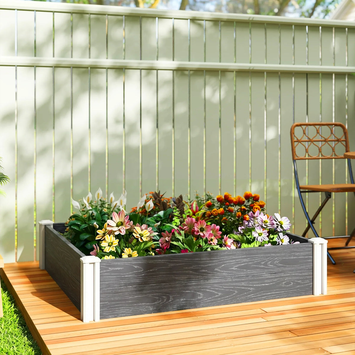 Dark grey vinyl raised garden bed with white corner posts filled with flowers