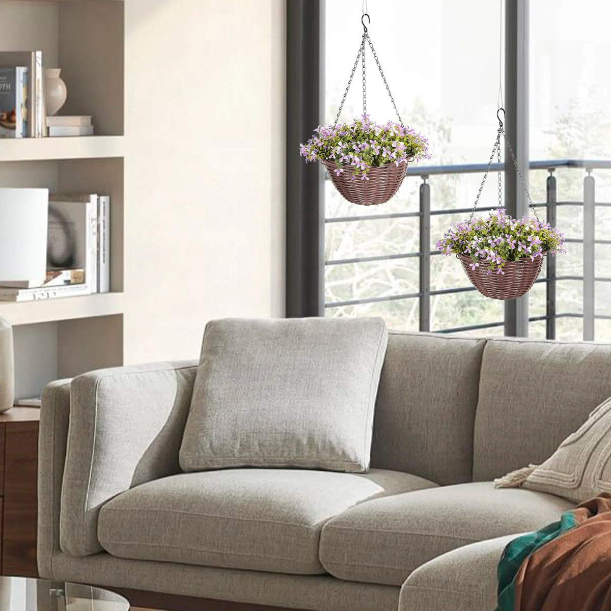 Set of 2 chain-hung baskets with purple faux blossoms and green leaves over a gray sofa