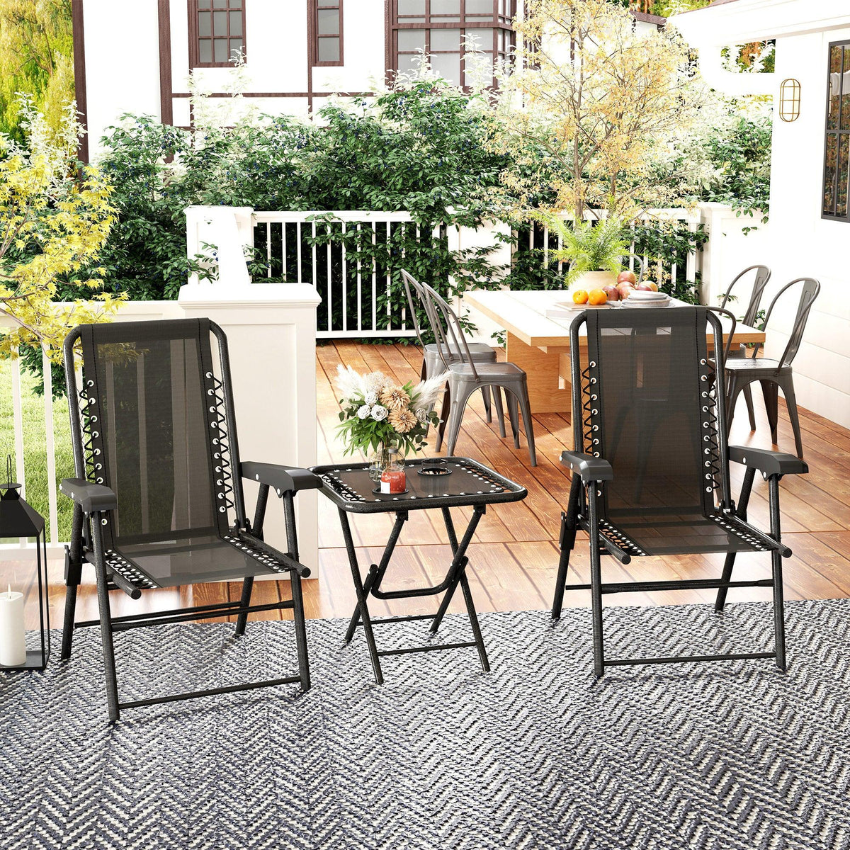 Black folding patio chairs with gray texteline backs and black metal legs, with table
