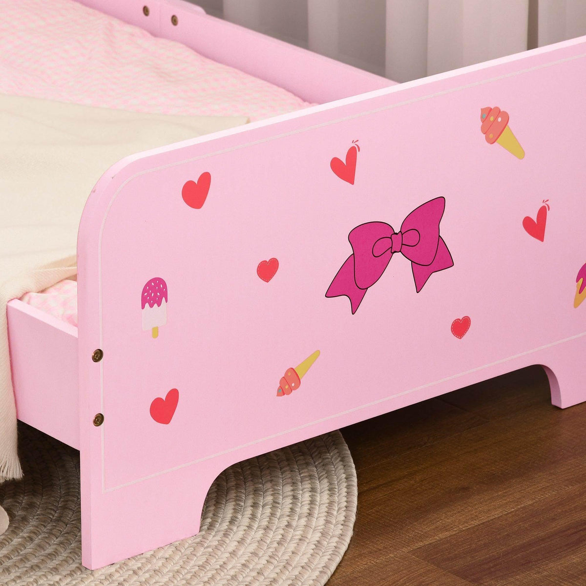 Close-up of pink toddler bed side panel with hearts, bows, and ice-cream icons