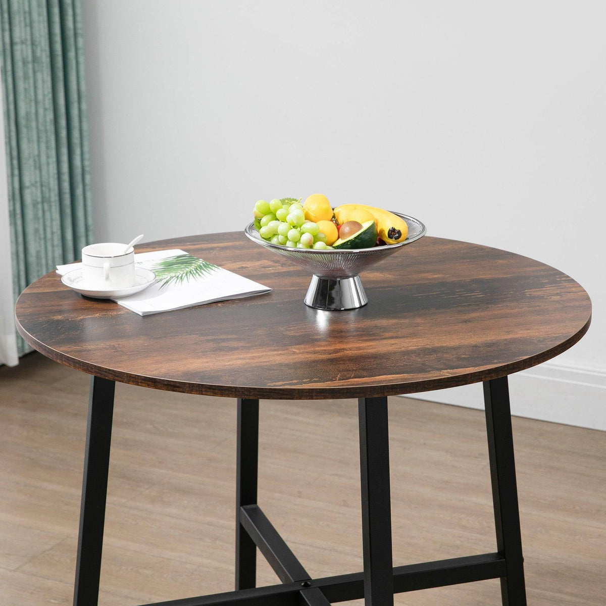 Brown round tabletop with fruit tray and black steel legs.