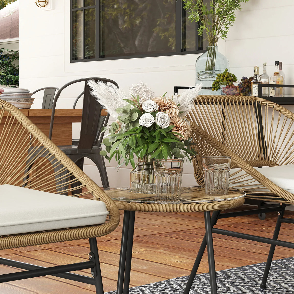 Two rattan wicker bistro chairs with white cushions and a round side table