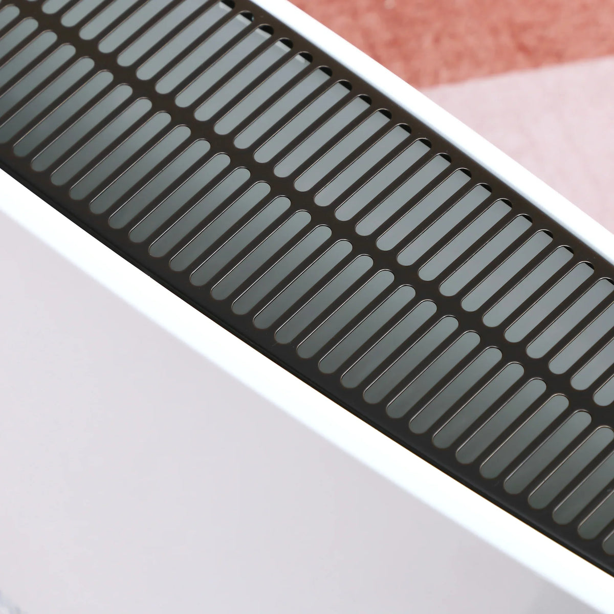 Black front vent grille on a white portable space heater with airflow slots