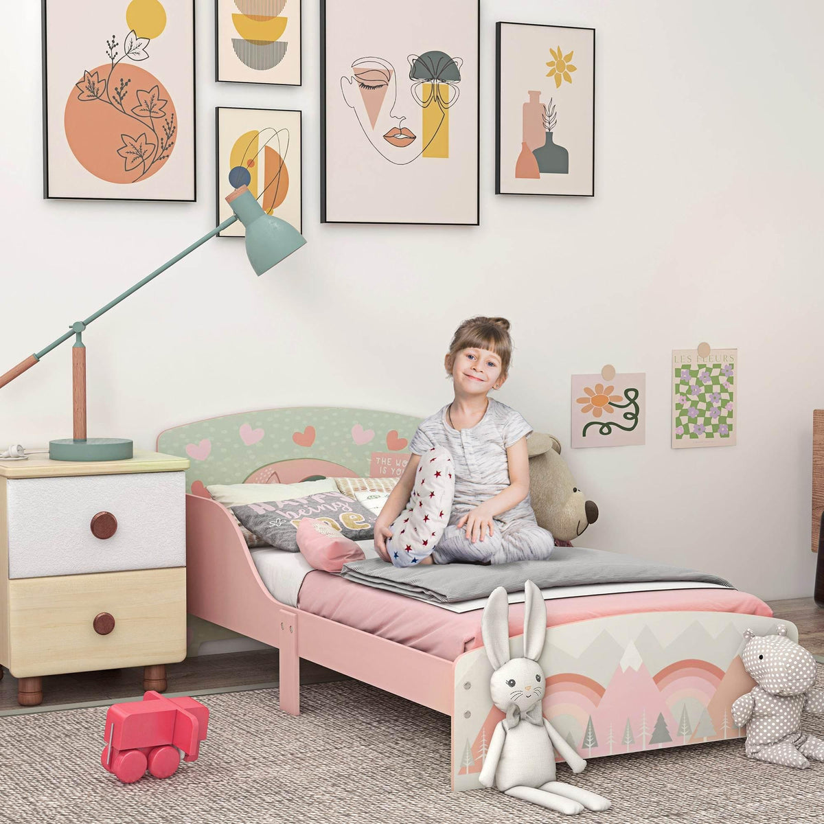 Pink toddler bed frame with rounded headboard, slatted base, and colorful animal print panels.