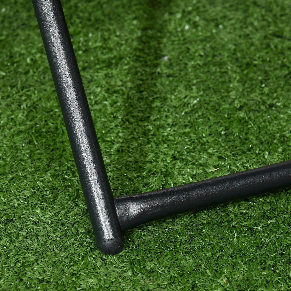 Black metal leg detail of square folding rattan coffee table on grass
