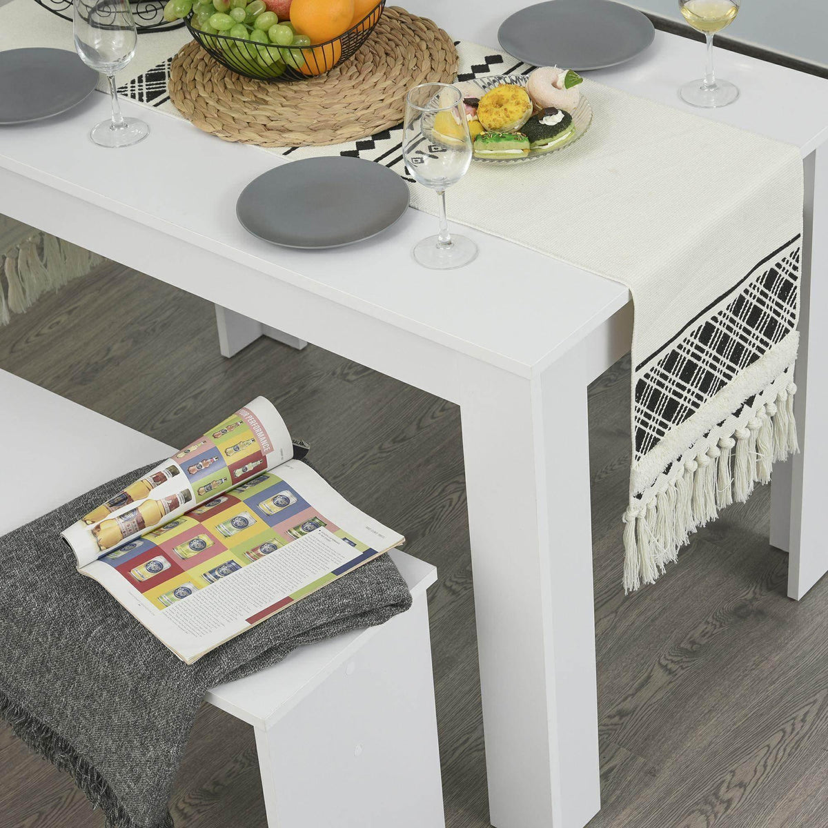 White dining table with two benches, tabletop setting with plates and glasses