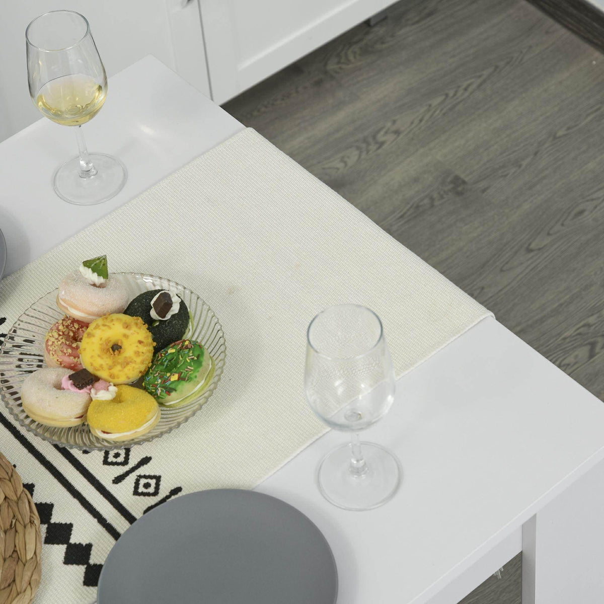 White dining table with two benches, table setting with plates and wine glasses