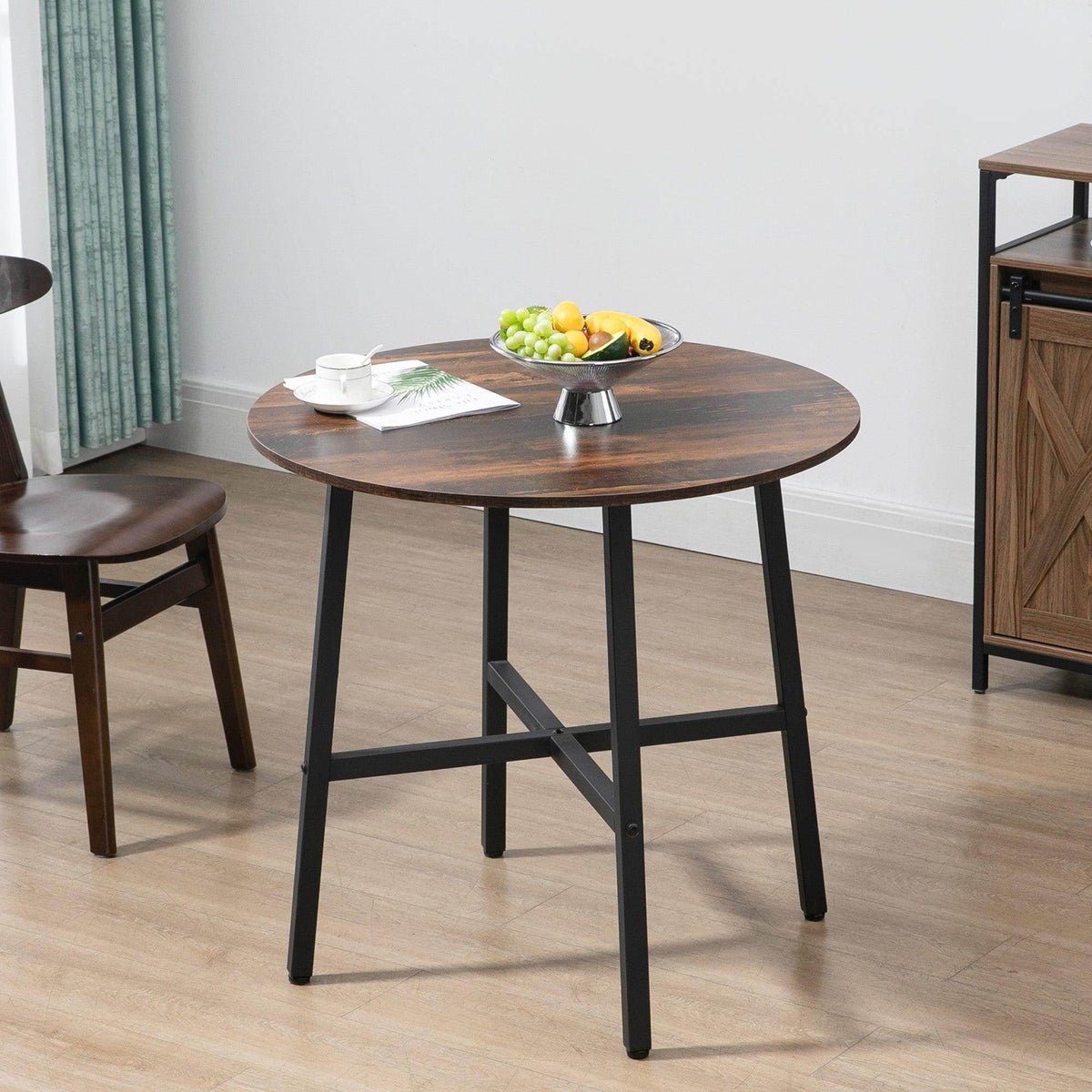 Brown round dining table with black steel legs and X-frame support.
