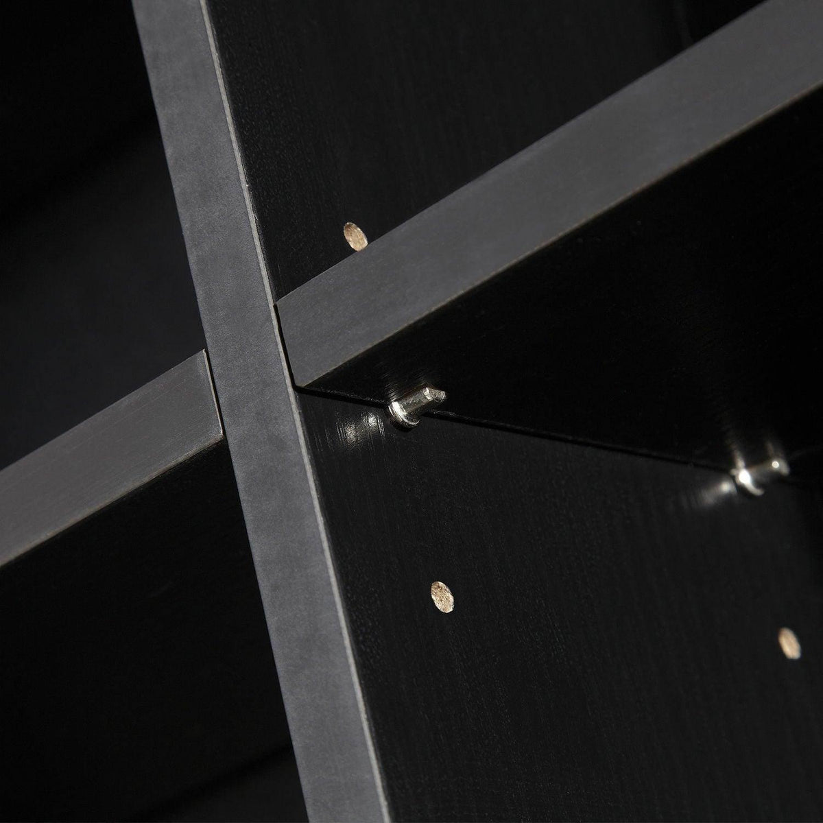 Close-up of black cabinet shelf corner with metal support pegs and pins