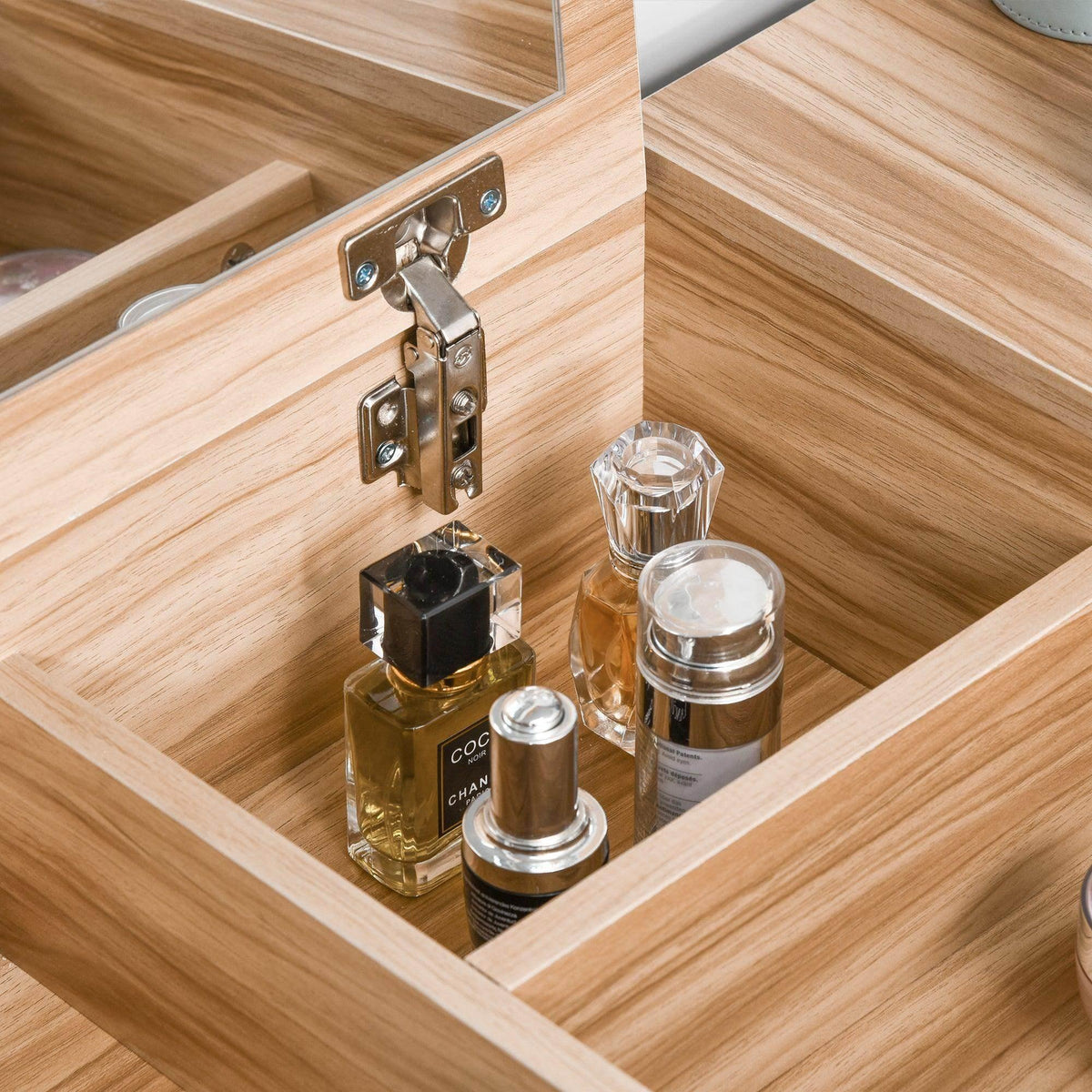 Light wood vanity drawer with gold-tone hinges and small glass bottles