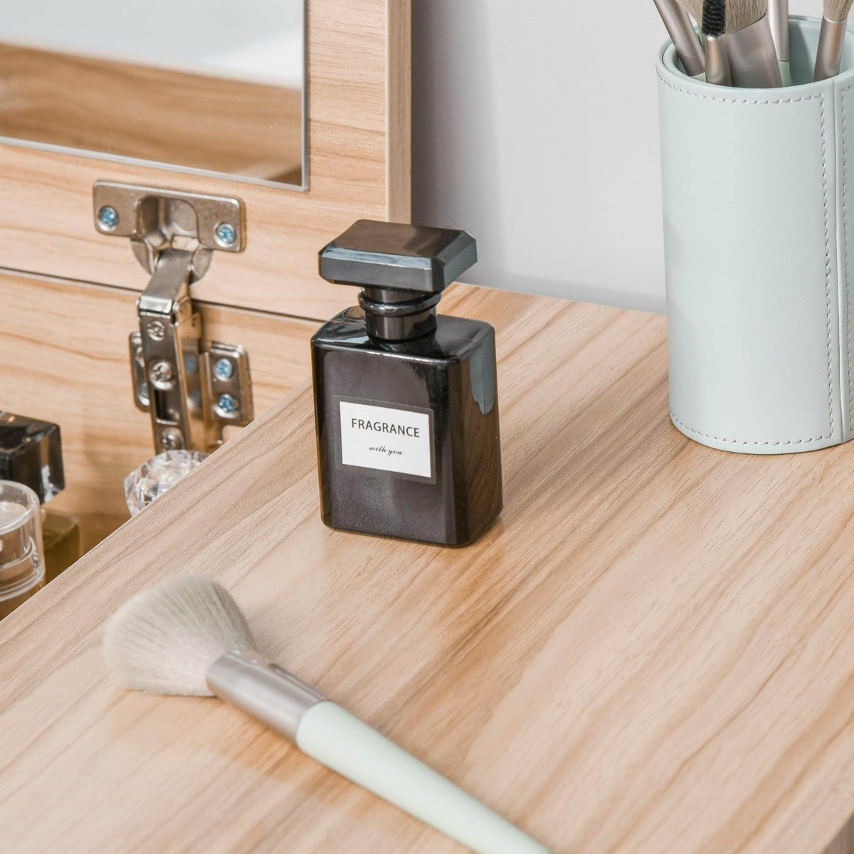 Light wood vanity tabletop with mirror hinge hardware and perfume bottles