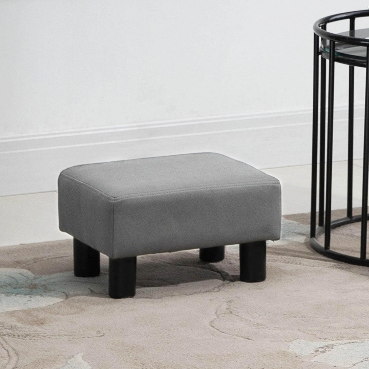 Grey upholstered foot rest ottoman with squared top and four short black legs