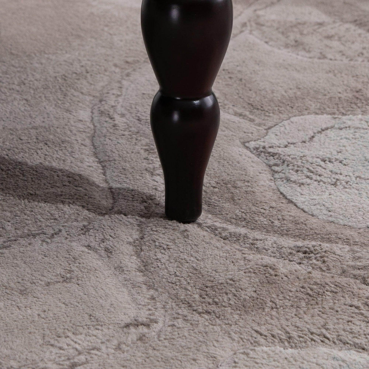 Close-up of dark carved wooden loveseat leg on carpet