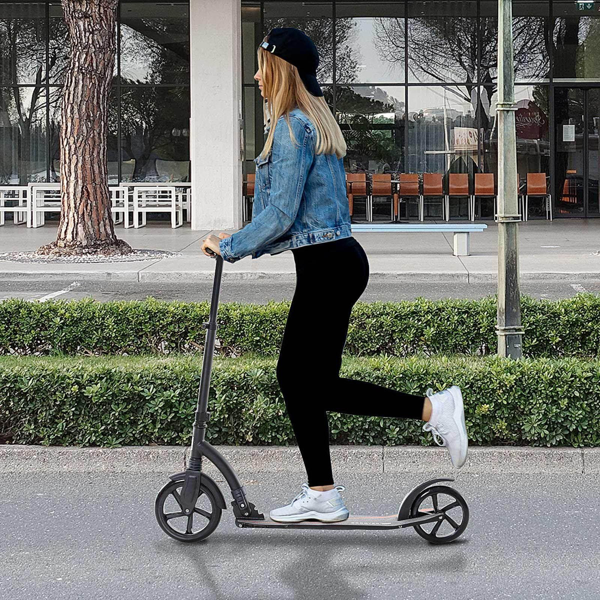 Foldable kick scooter in white with black wheels and gray deck, side view with rider