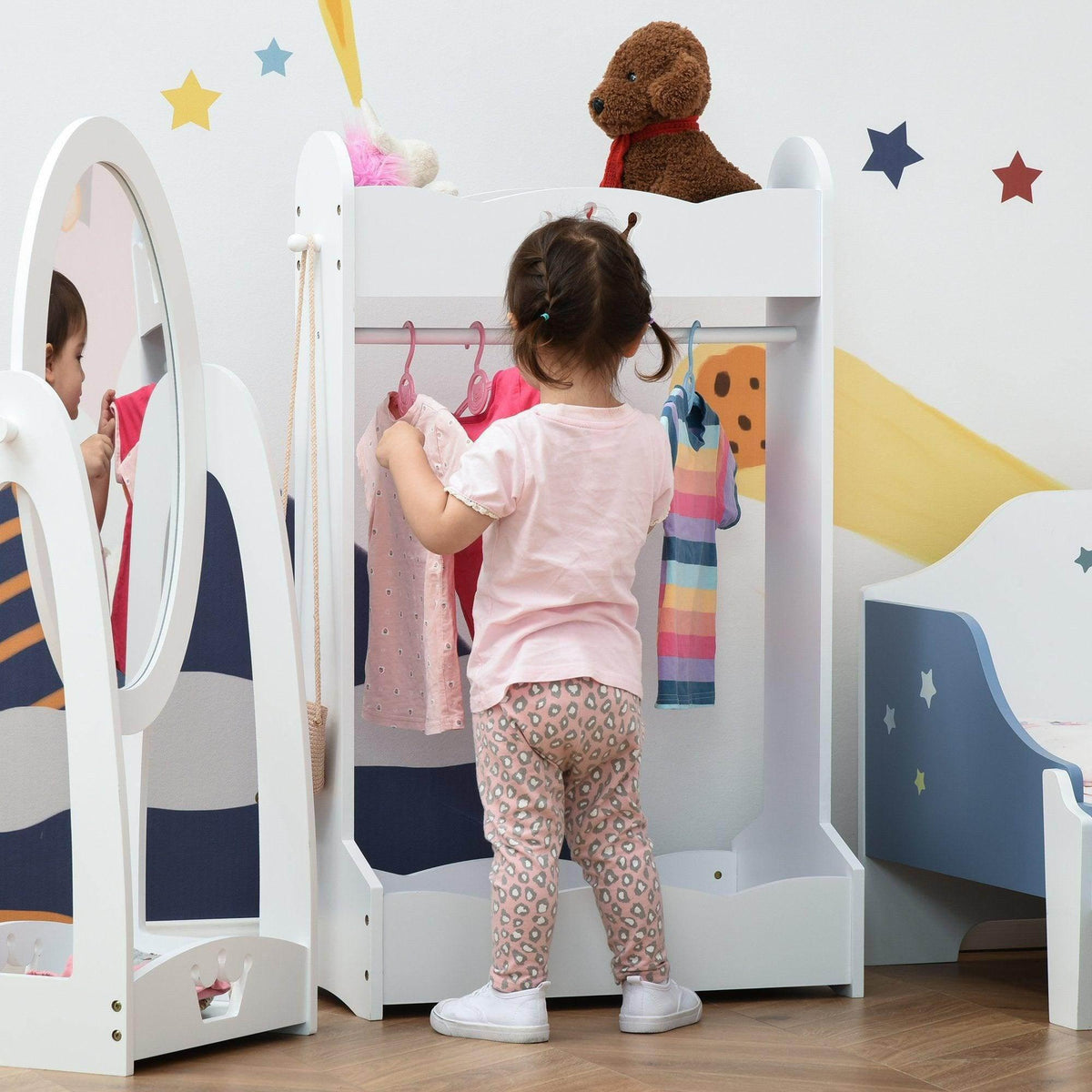 White kids wooden clothes rack with hanging bar and shelves; toddler reaching for clothes