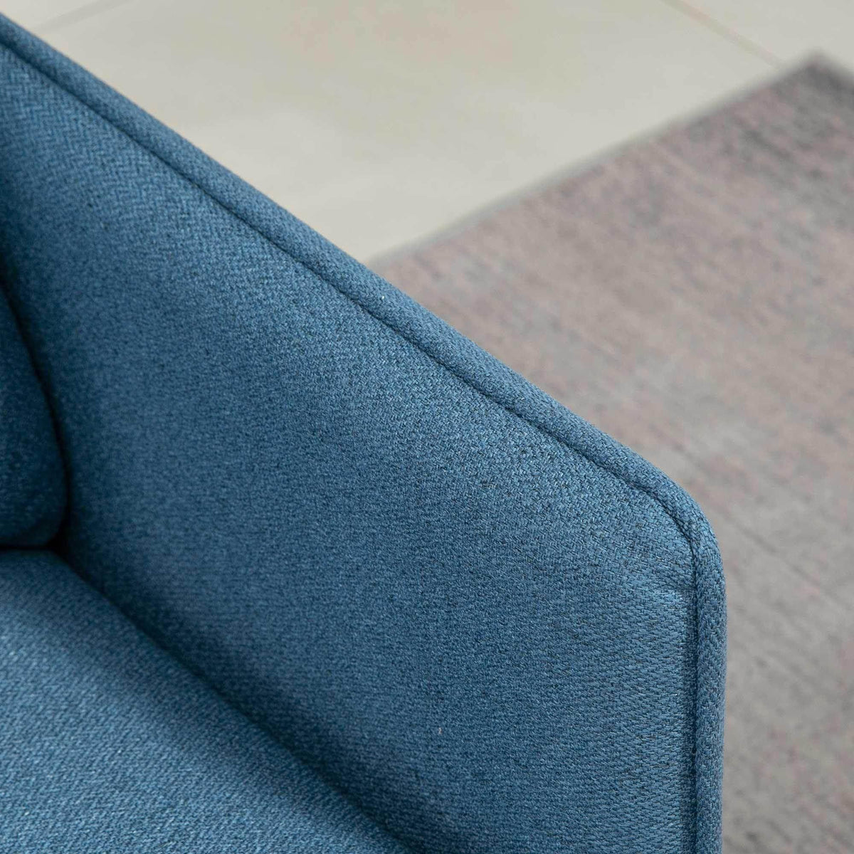 Dark blue upholstered armrest with curved seam detail on the loveseat