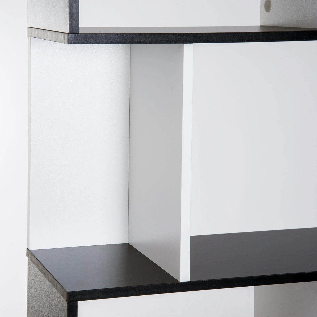 Close-up of white interior corner and black shelf edge on a 5-tier bookcase.