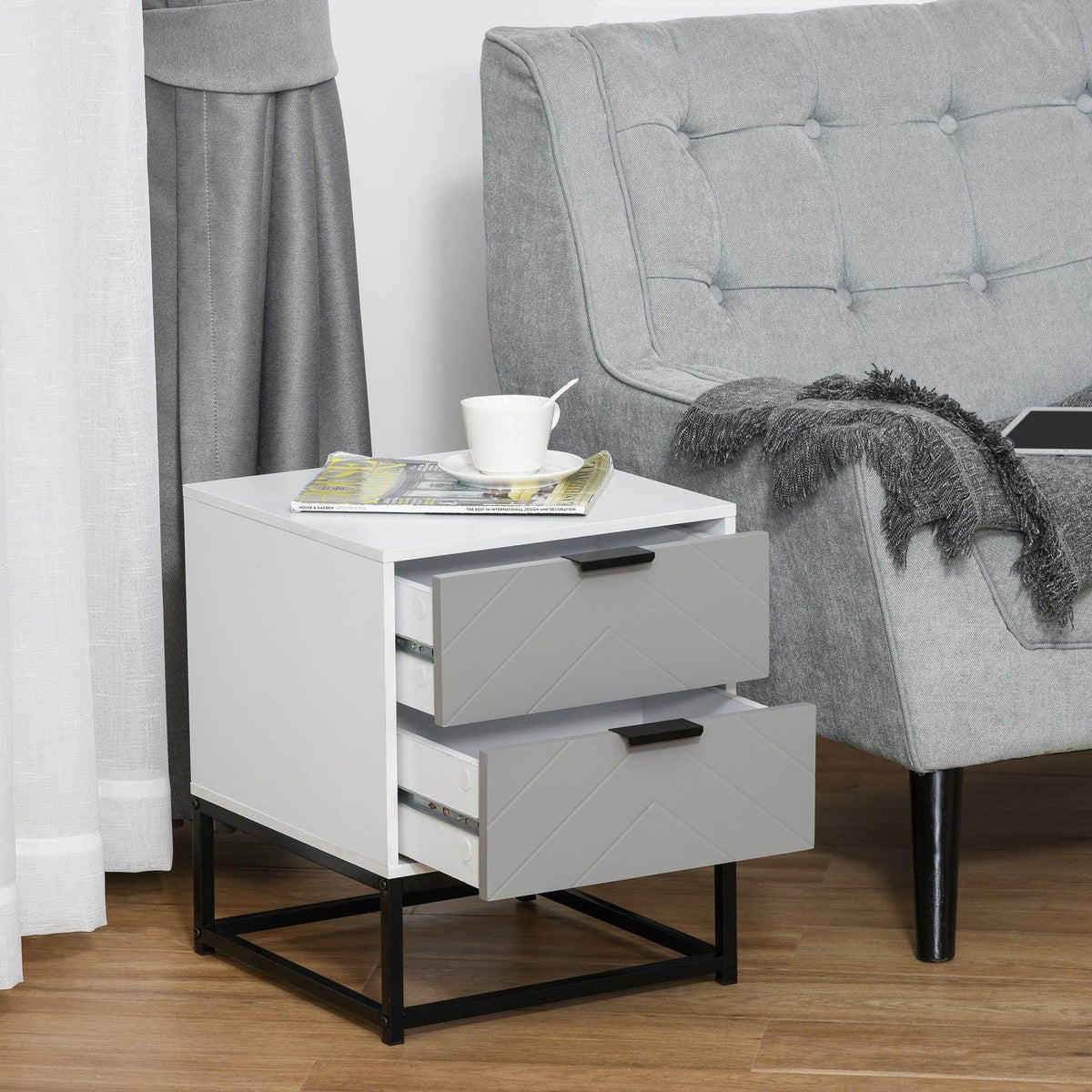 White bedside cabinet with 2 drawers on black metal base near upholstered chair