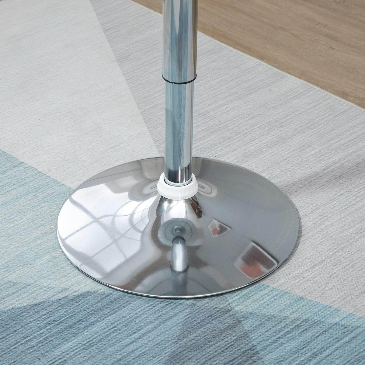 Chrome pedestal base with wide circular base plate under a white round tabletop.