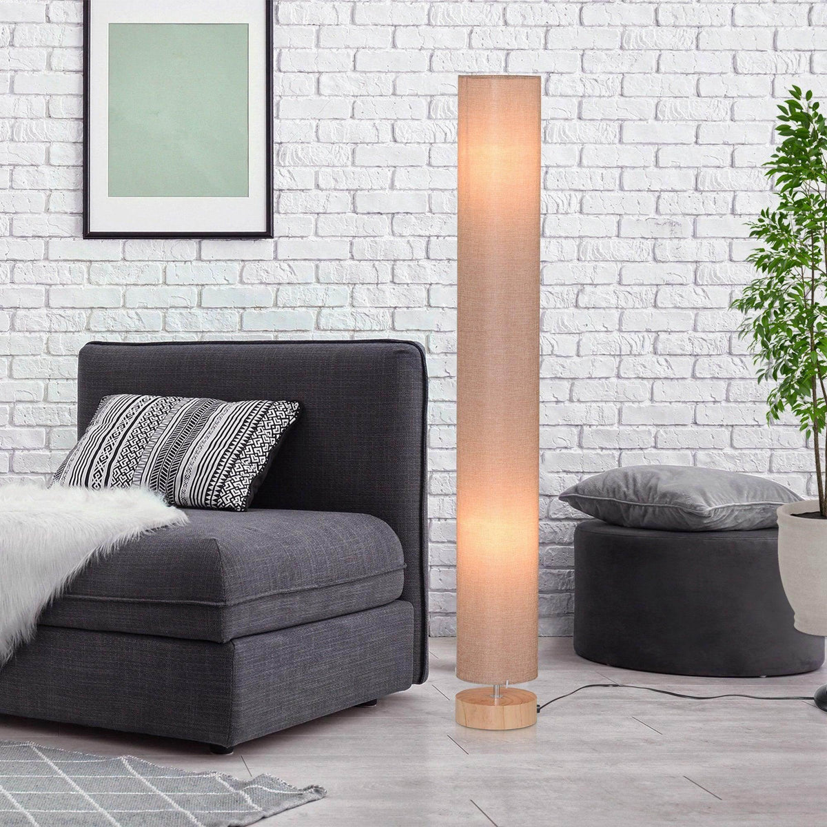 Tall linen-shade floor lamp with wood base beside a sofa and cushions