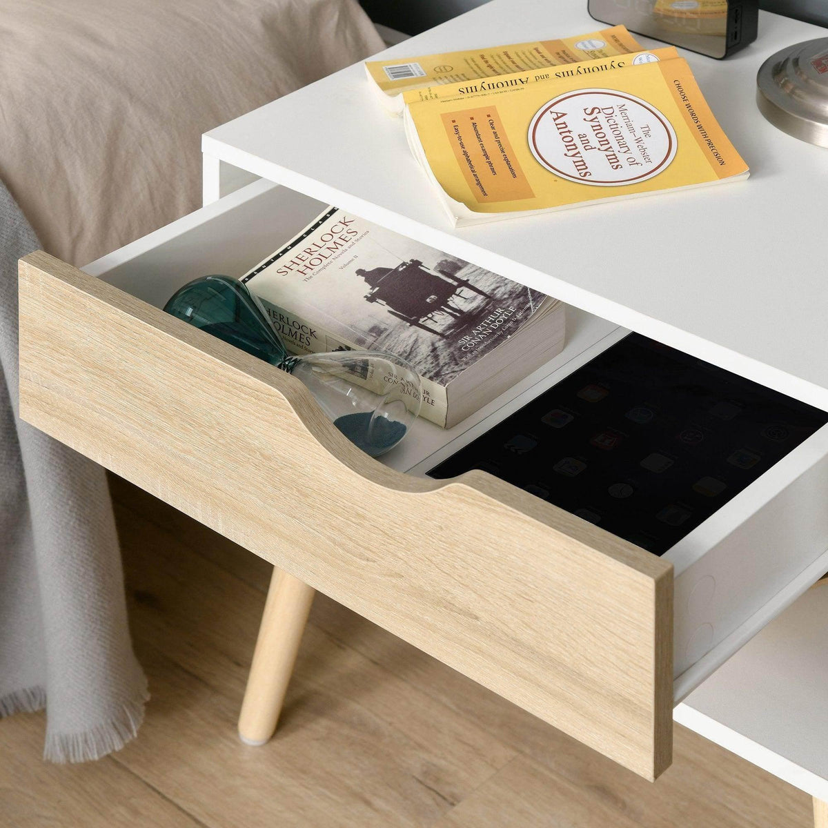 Close-up of nightstand drawer with cut-out handle; light wood front and white frame