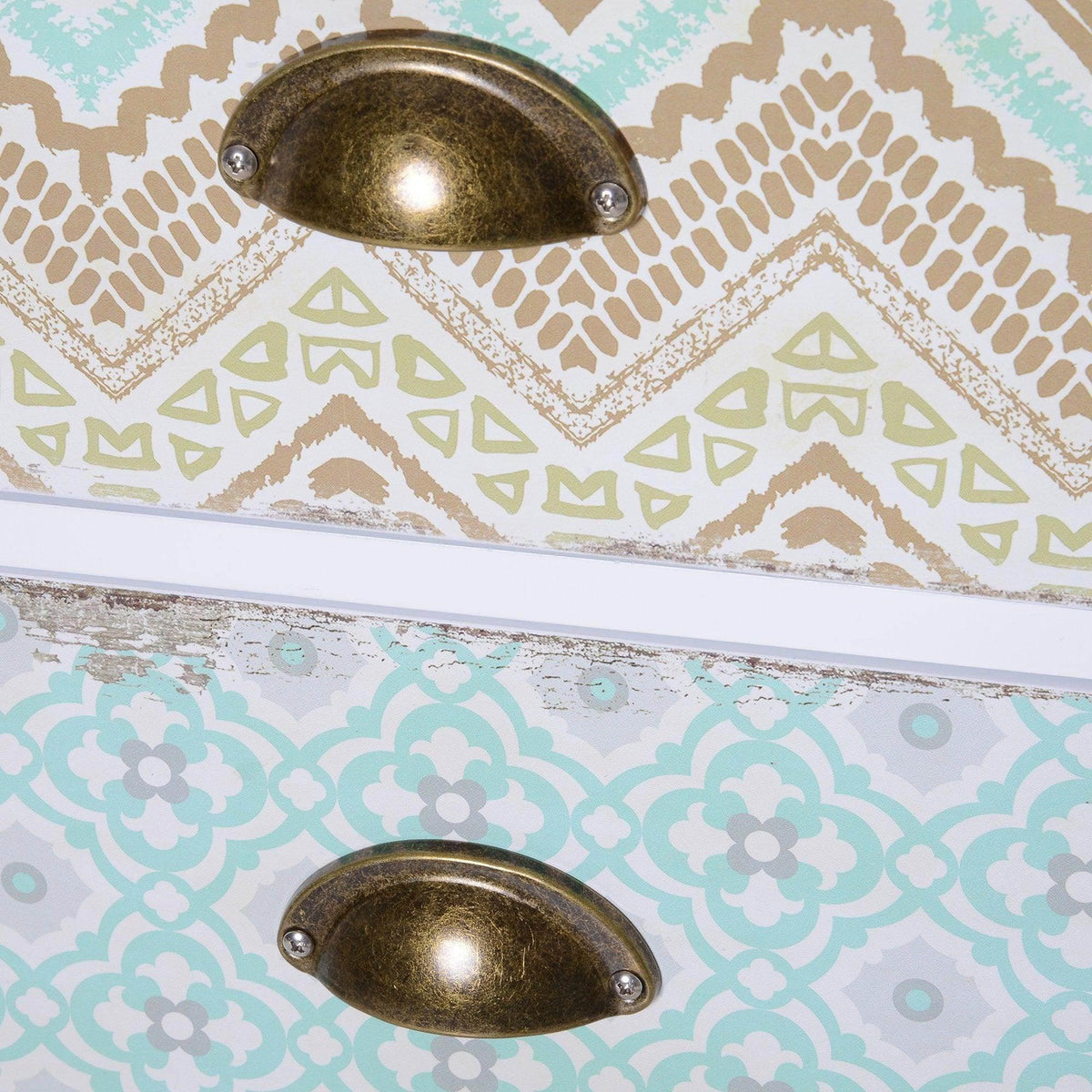 Close-up of decorative patterned drawer fronts with bronze handle pulls