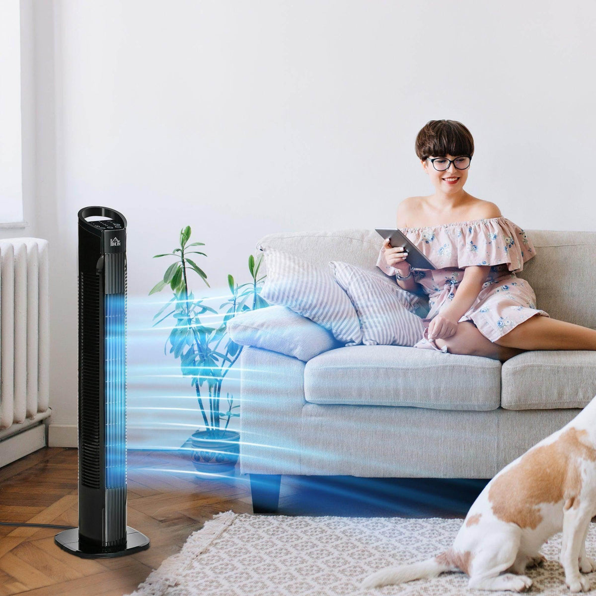 Black tower fan standing on the floor beside a sofa and rug.