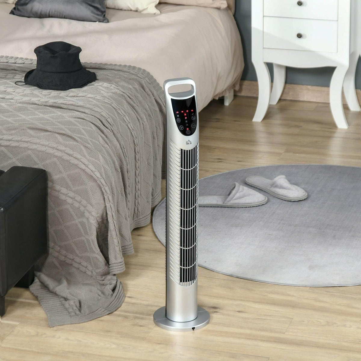 White tower fan with black control panel standing on a floor