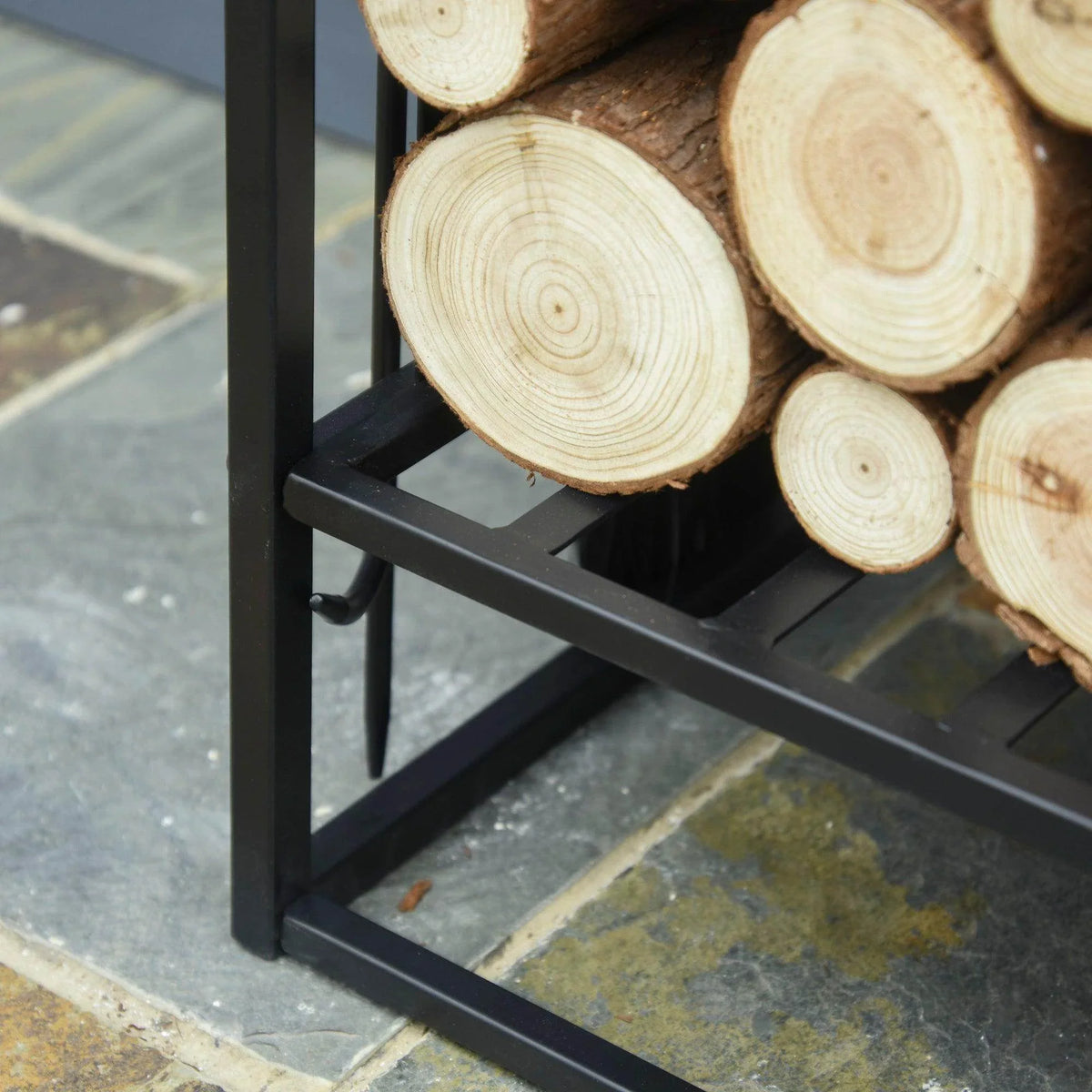 Close-up of cut firewood logs resting on the black slatted rack shelf.