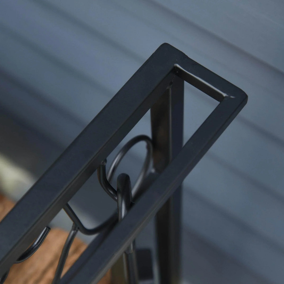 Close-up of the firewood rack top rail and curved hook holders on the frame.