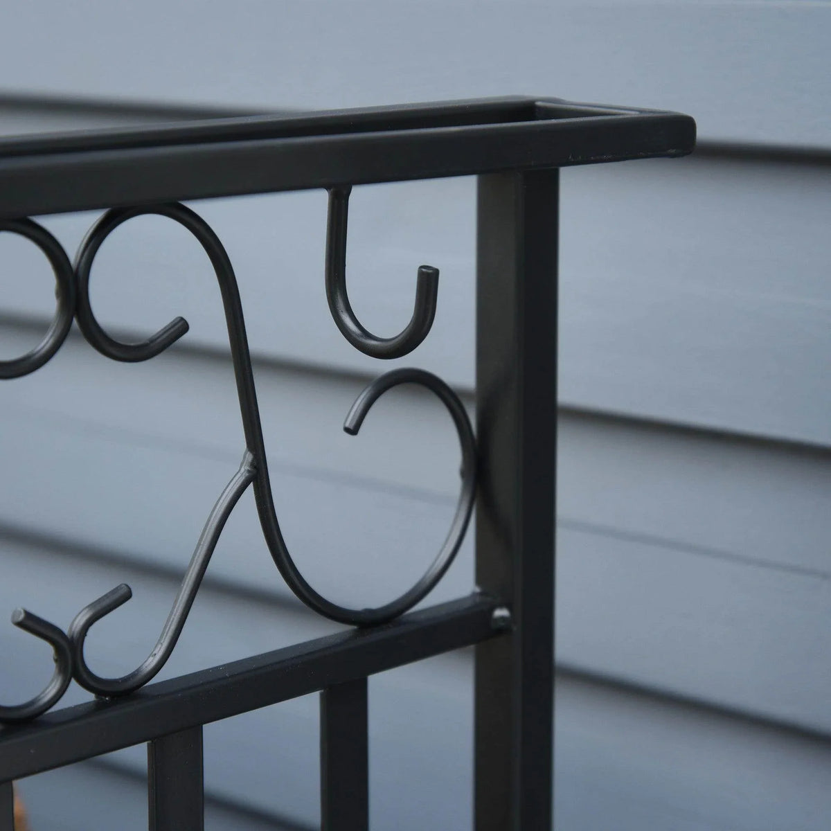 Close-up of decorative hook set on the black firewood rack side frame.