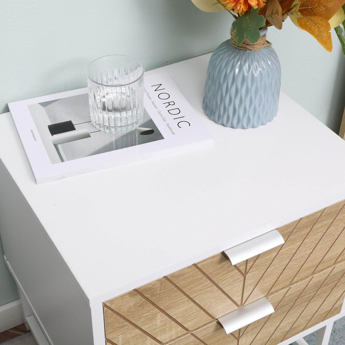 White bedside table with open drawer and gold-toned chevron-pattern front, white tabletop