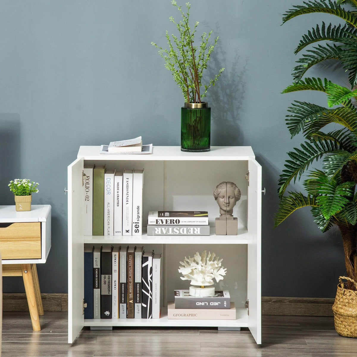 White storage cabinet open to show two interior shelves with books and decor
