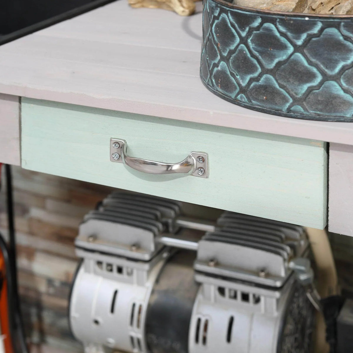 Potting table drawer with chrome pull handle and stored garden equipment below
