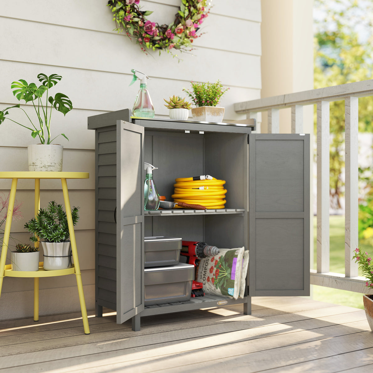 Grey wooden garden shed with potting table, open doors, shelving for tools and supplies.