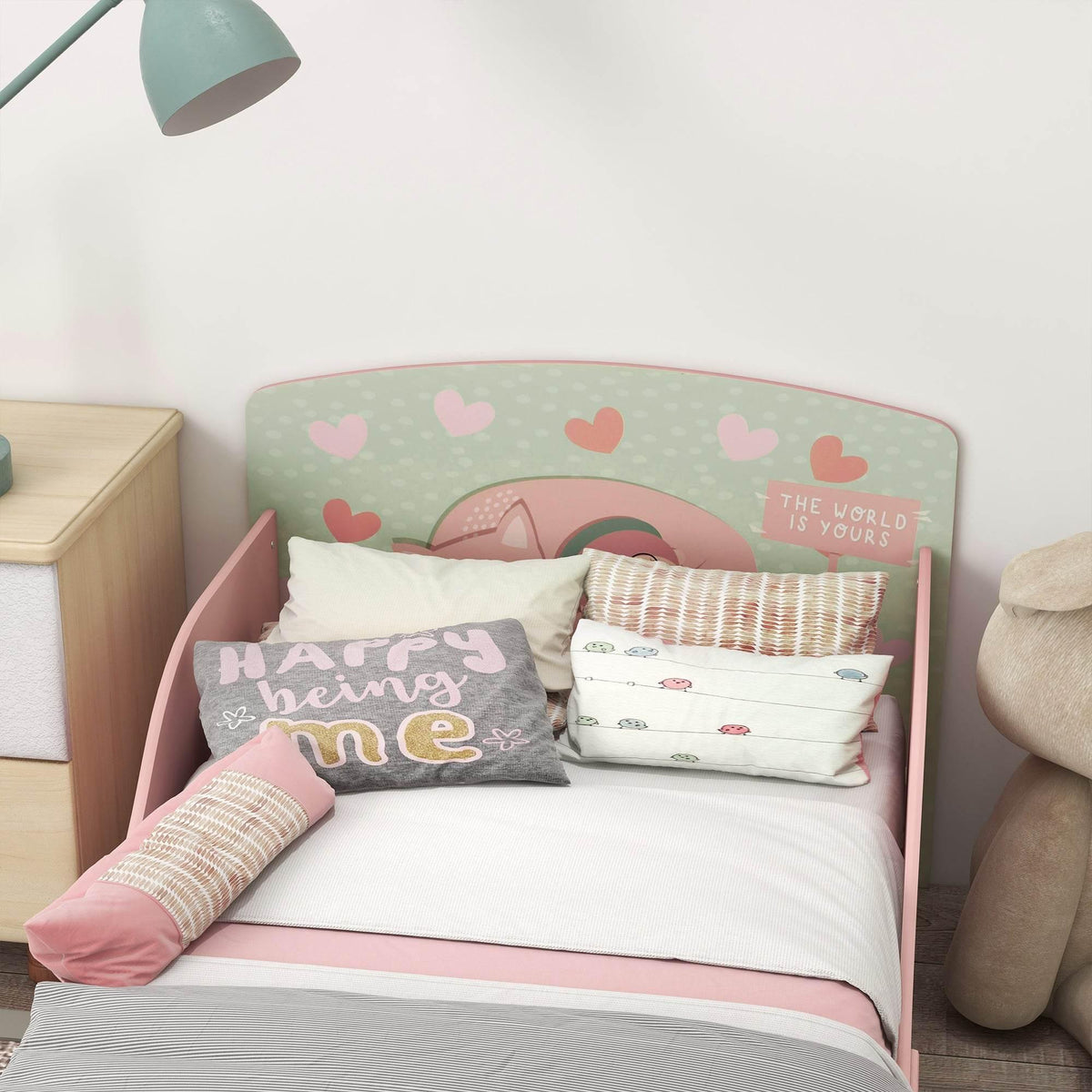 Pink toddler bed frame with padded-looking side rails and woodland animal print back panel.