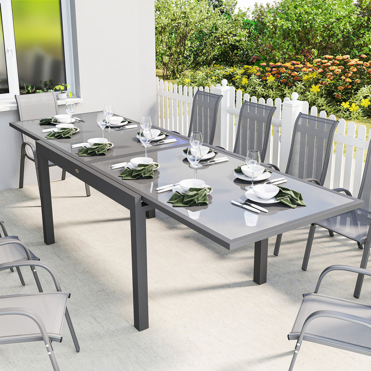 Grey extending outdoor dining table with tempered glass top, set for outdoor meals