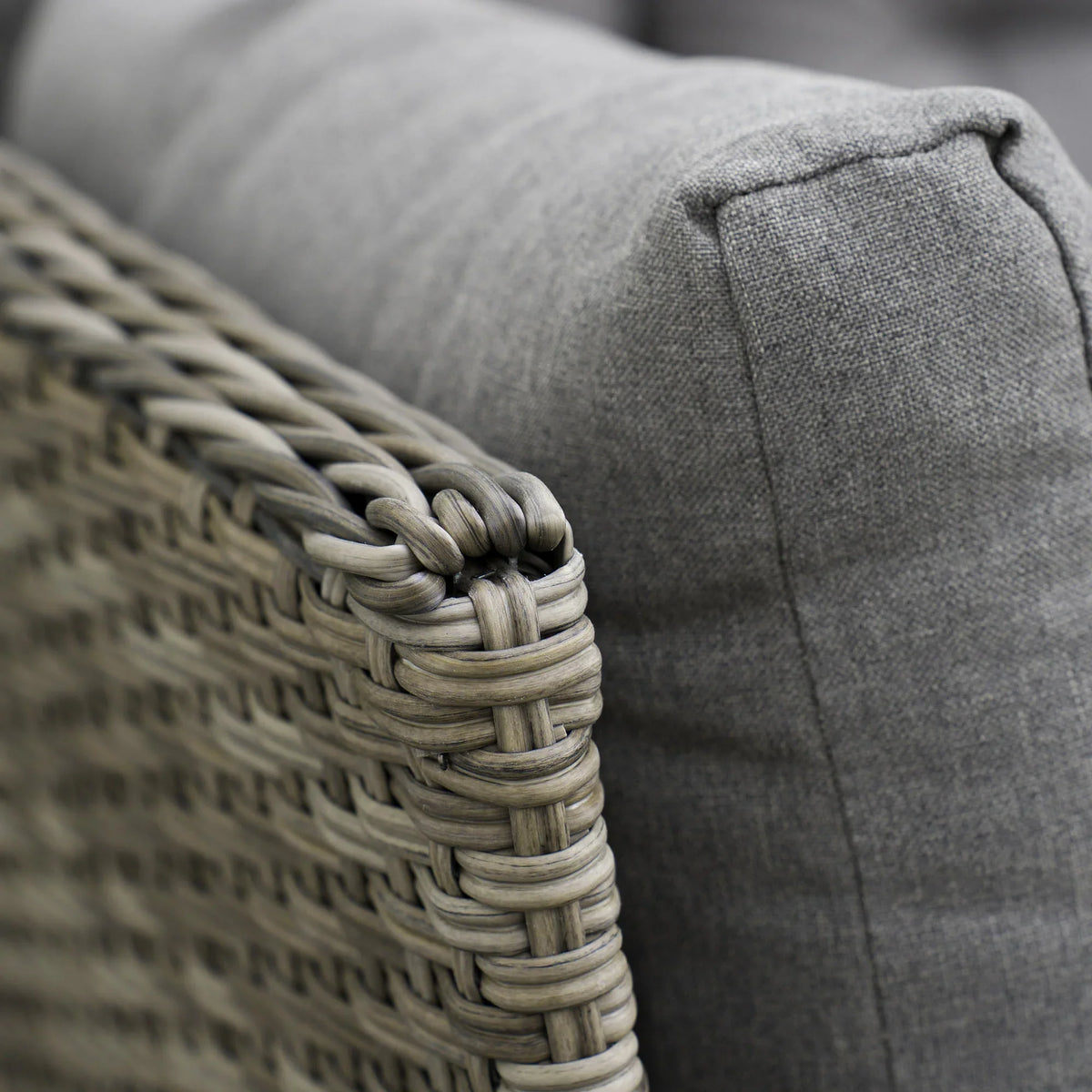 Outdoor rattan sofa armrest corner with light gray seat cushion and woven detail