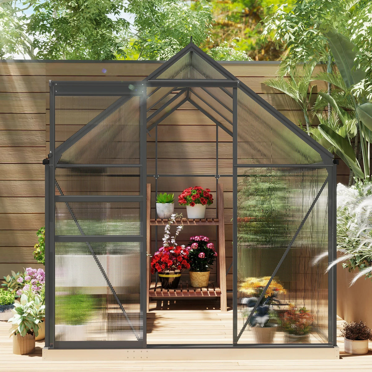 Polycarbonate greenhouse with dark grey frame, front opening and potted plants