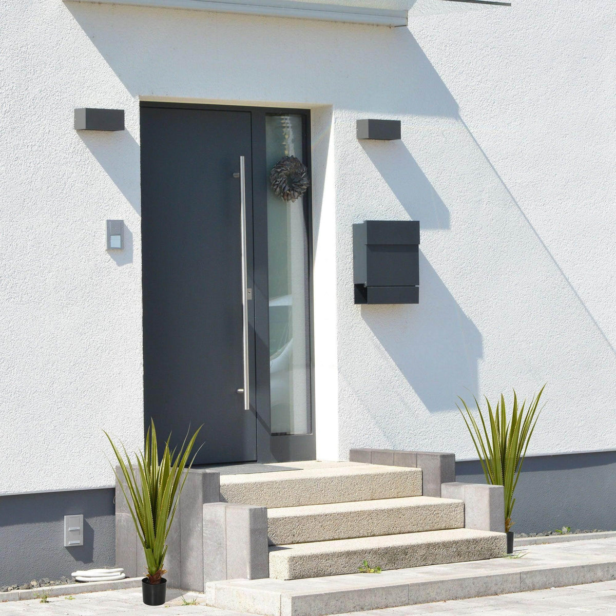 Set of 2 artificial agave succulents in black pots on outdoor steps, spiky green leaves