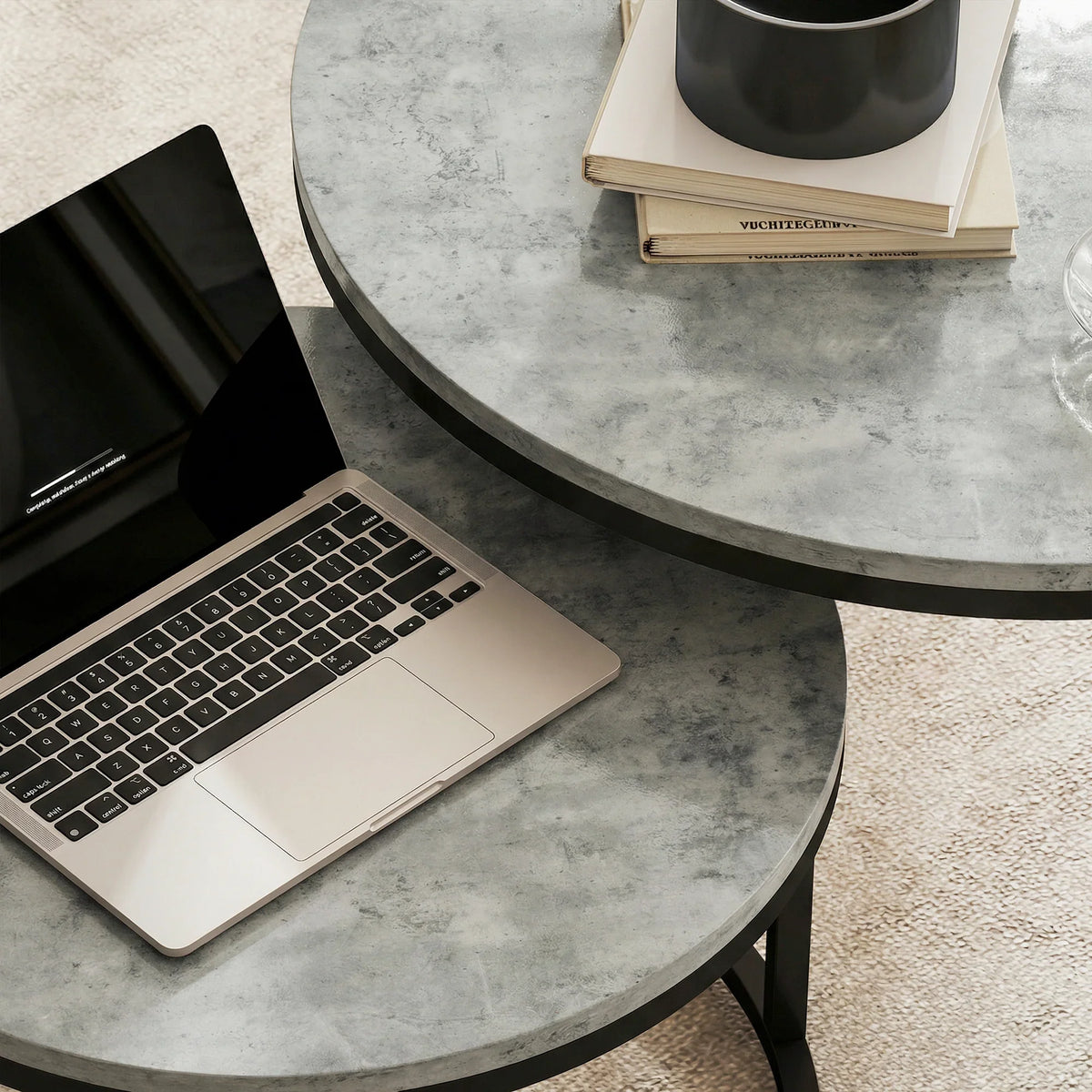 Grey cement-effect round table top with laptop on black metal nesting table