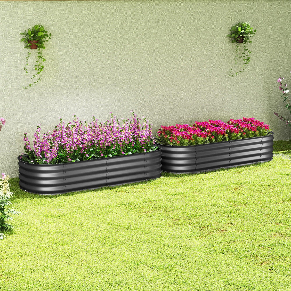 Two dark grey raised garden beds with safety edging, planted with pink flowers