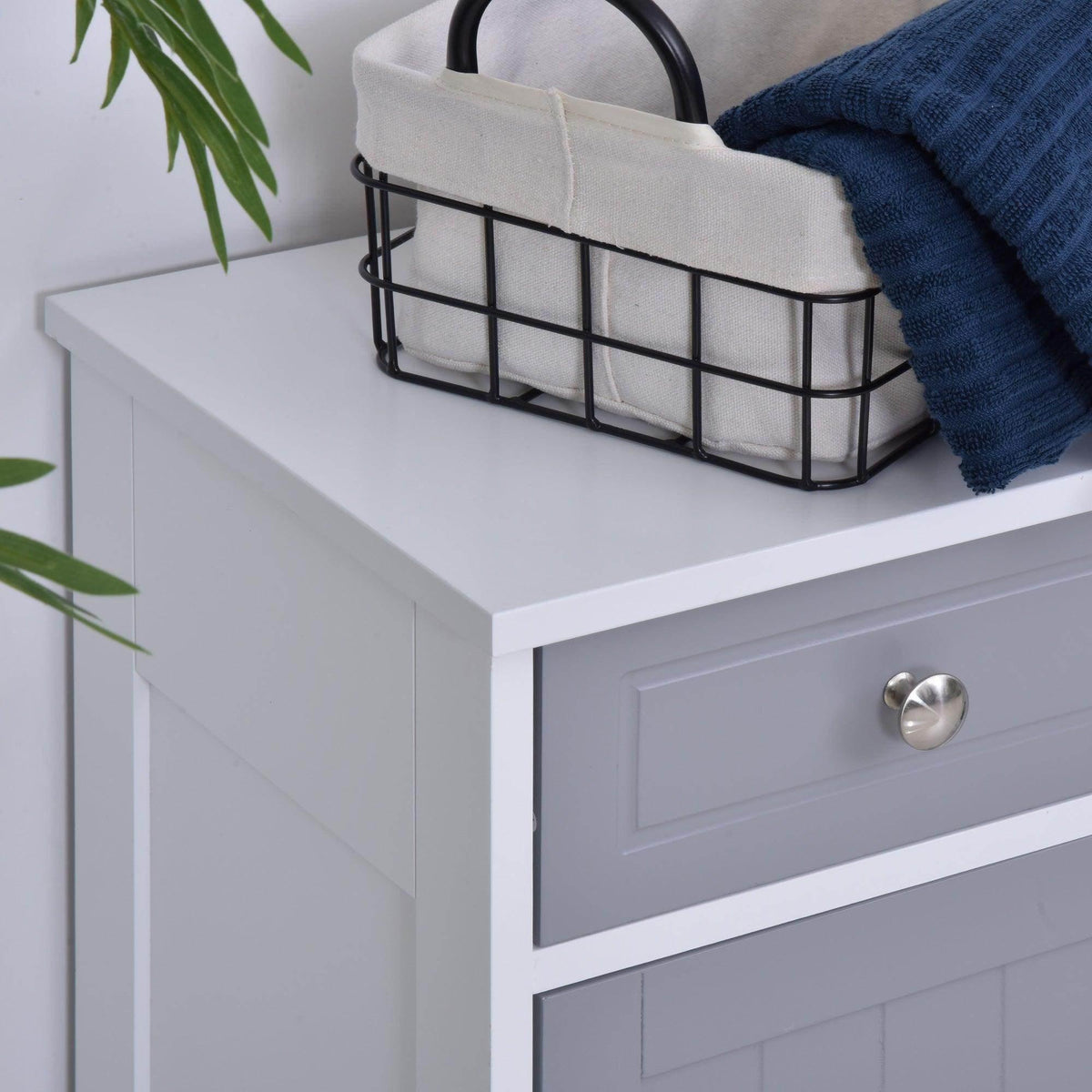 Grey cabinet top shelf with metal basket and a front drawer with round metal knob.