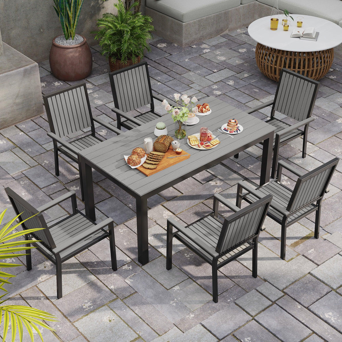 Grey outdoor dining set on patio with rectangular table and 6 stackable chairs