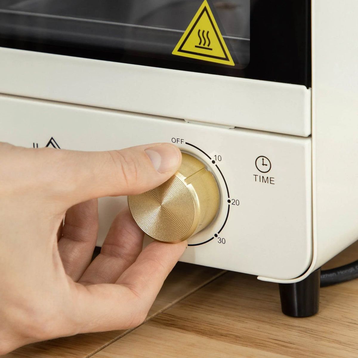 Cream white mini convection oven temperature knob being turned by hand