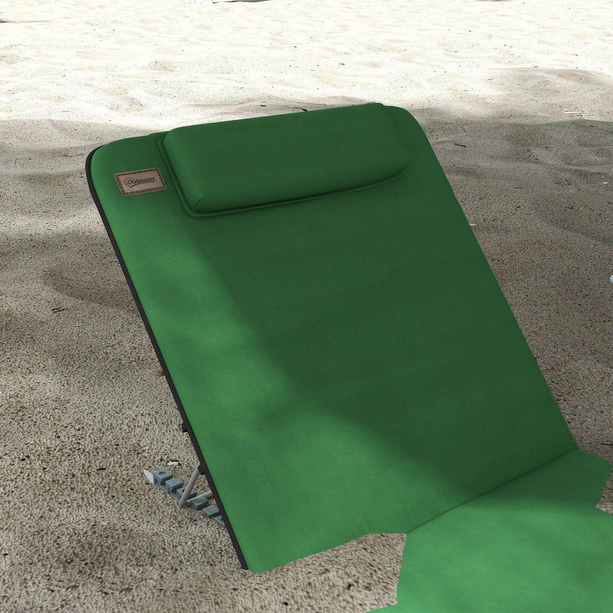 Green reclining chair with attached pillow and foldable metal frame, close-up on sand